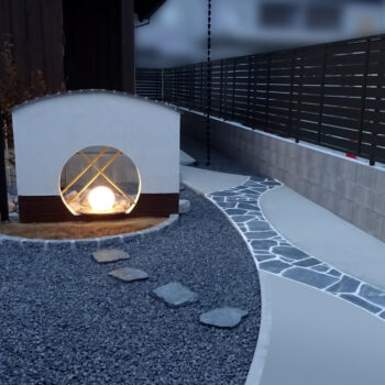 丸い窓がある門柱と天然石乱張りのアプローチ